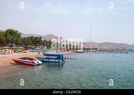 Aqaba, Jordanien - Mai 18, 2018: Aqaba, öffentlichen Strand mit Palmen und Sportboote, Menschen schwimmen Stockfoto