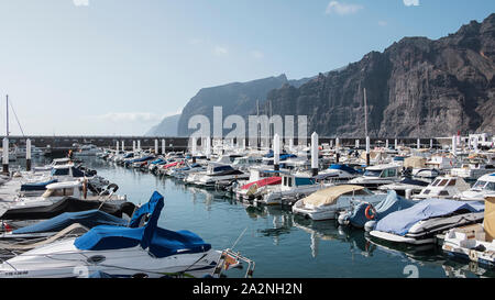 Die yacht Marina, wie von der Stadt pier gesehen, mit der berühmten riesigen Felsen hinter als Acantilados de Los Gigantes, Teneriffa, Kanarische Inseln, Spanien Stockfoto