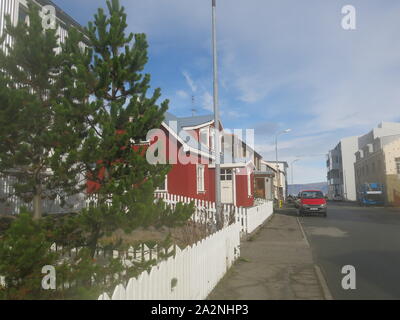 Die kleine Stadt Isafjordur verfügt über hell eingerichtete Gebäude im Gegensatz zu den vulkanischen, bergige Landschaft der Region Westfjorde Islands farbige Stockfoto