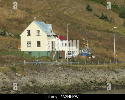 Die kleine Stadt Isafjordur verfügt über hell eingerichtete Gebäude im Gegensatz zu den vulkanischen, bergige Landschaft der Region Westfjorde Islands farbige Stockfoto