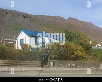 Die kleine Stadt Isafjordur verfügt über hell eingerichtete Gebäude im Gegensatz zu den vulkanischen, bergige Landschaft der Region Westfjorde Islands farbige Stockfoto