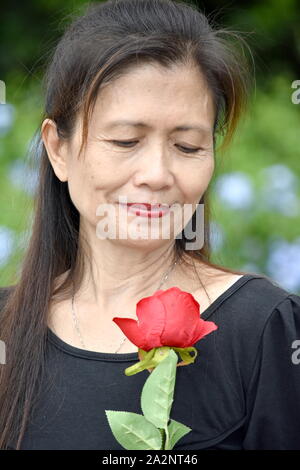 Asiatische Frau Senior und Traurigkeit mit einer Blume Stockfoto