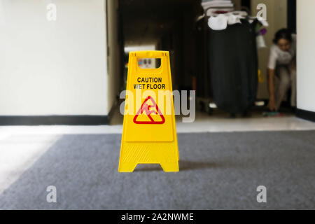 Schild, Warnung Vorsicht nasser Boden, Reiniger auf dem Hintergrund Stockfoto