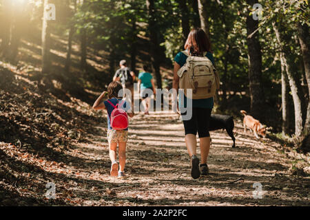 Mutter und Tochter zu Fuß durch einen Pfad mit ihren Hunden im Wald tragen Rucksäcke und Kurzschlüsse Stockfoto