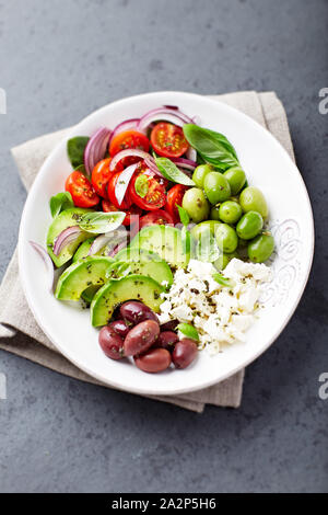 Mediterranem Gemüse Schüssel mit Feta, Kirschtomaten, Avocado und organische Grün und Kalamata Oliven, Gewürzen und frischem Basilikum. Stockfoto