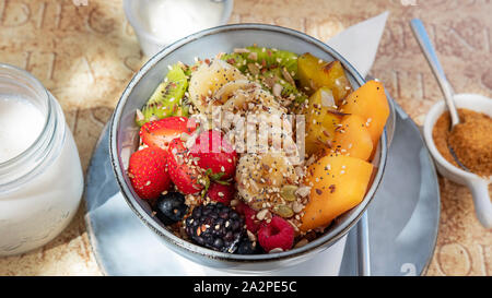 Leckeres und gesundes Frühstück, Müsli und Obst Schüssel mit Erdbeeren, Bananen, Kiwis, Sternfrucht und Papaya, Hafer und nahrhafte Nüsse Stockfoto