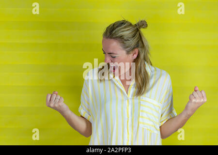 Schöne junge Frau glücklich und aufgeregt zum Ausdruck gewinnen Geste, Gelb background-image Stockfoto