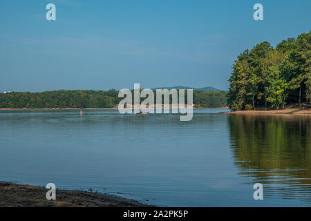 Ein Fischerboot der Rückkehr zum Boot Rampe aus Angeln im See mit Bergen im Hintergrund auf einem dunstigen sonnigen Nachmittag im frühen Herbst Stockfoto