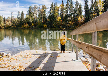 Junge stehend an einem See an einem sonnigen Herbsttag Stockfoto