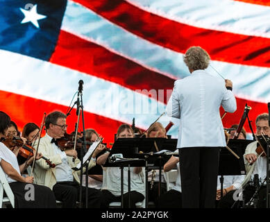 East Islip, New York, USA - 13. Juli 2019: Der Long Island Konzert Orchester führt Sie kostenlos bei Heckscher State Park mit einer amerikanischen Flagge Kulisse. Stockfoto