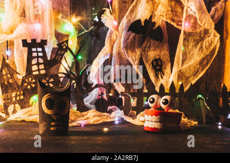 Hexen Haus mit Grab und beängstigend Baum geschnitten aus schwarzem Papier, neben ihm gibt es Eulen und Kiefer auf Holz- Wand mit einem Spinnennetz und LED-Kranz. Kopieren Stockfoto