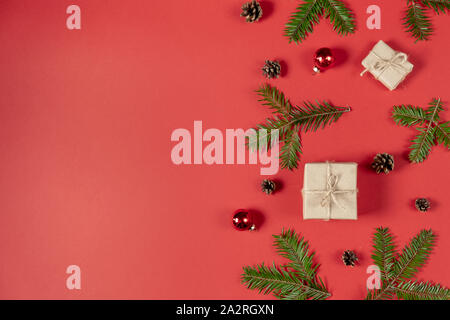 Weihnachten und Winter Zusammensetzung. Rahmen aus Tanne, Kiefer und handgearbeitete Geschenkboxen auf Pastell roten Hintergrund. Weihnachten, Winter, neues Jahr c Stockfoto