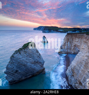 Der Himmel fängt Feuer über dem Ikonischen sea Stacks in Freshwater Bay auf der Isle of Wight, als Wellen gegen die Basis der hohen Kreidefelsen schoß. Stockfoto