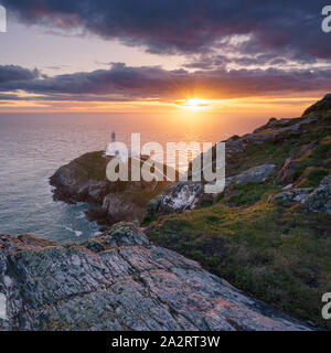 Die untergehende Sonne highlights South Stack Leuchtturm auf der Insel Holyhead, Wales, von der Klippe auf einem blustery Abend im Frühjahr gesehen. Stockfoto