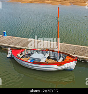 Kleines Fischerboot, das auf dem Ponton in Wells-next-the-Sea bei Low Tide an der Norfolk-Küste, Großbritannien, festgemacht ist Stockfoto