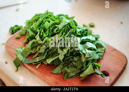 Junge grüne Sauerklee geschnitten für Borschtsch und Salat liegt auf einem Schneidebrett, rustikaler Stil, am Morgen in der Sonne. Kopieren Sie Platz. Stockfoto