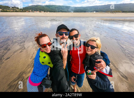 Freunde stehen auf dem Strand, selfie Foto. Sind eine Gruppe von jungen Menschen, die Freunde, die selfie am Sandstrand auf Sommer Eveni Stockfoto