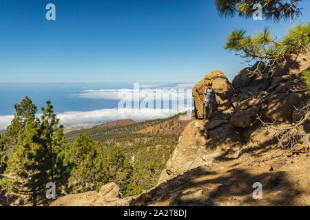 Steinigen weg von Pinien am sonnigen Tag umgeben. Strahlend blauer Himmel und einige Wolken am Horizont. Rocky tracking Straße in trockenen Berggebiet mit Stockfoto