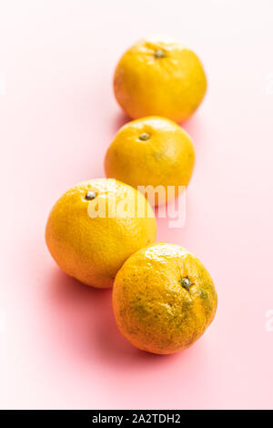Frische gelb Mandarinen auf rosa Hintergrund. Stockfoto