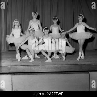 1960er Jahre, historisches Schulballett, auf einer Holzbühne posiert eine Gruppe junger Mädchen in ihren Ballettkostümen - ein Kleid, das als Tutu bekannt ist - anmutig für ein Foto, England, Großbritannien. Das Wort Ballett bedeutet "kleiner Tanz". Stockfoto