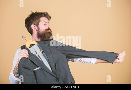 Bei Schneider Haus. Master Tailor. Bärtiger Mann Meßhülse Länge der Anzug Jacke in der Schneiderei. Hipster Holding maßgeschneiderte Mantel an Department Store. Kleidung und Schneiderei. Stockfoto