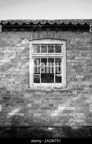 Alte verwitterte Holz- Fenster in Red Brick Wall auf ländlichen Stabile Hof Nebengebäude Stockfoto