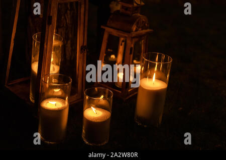 Viele brennende Kerzen in Glas und Holz- Laternen auf dunklem Boden Außenpool bei Nacht. Romantische Partei. Diwali Feuer Urlaub Stockfoto