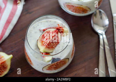 Gesundes Frühstück aus natürlichen Zutaten. hausgemachten Joghurt, Scheibe der Feige, Chia Samen und Joghurt in Gläsern auf dem hölzernen Hintergrund, Ansicht von oben. Stockfoto