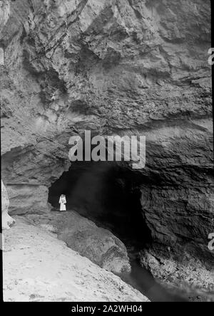 Lantern Slide-Frau am Eingang der Höhle, Victoria, Datum unbekannt, Schwarze und Weiße Glas Laterne Folie der Frau, die am Eingang zu einer Höhle, fotografiert von A.J. Campbell. Es handelt sich um eine große Sammlung von Bildern durch A.G und sein Vater A.J Campbell in der A.j. gehalten Campbell Sammlung von Museum Victoria Stockfoto