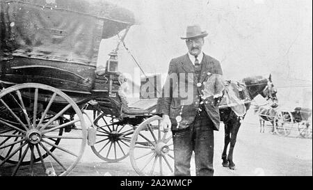 Negative - Mann stand neben Horse-Drawn Cab Draußen Bahnhof, Ballarat, Victoria, ca. 1920 Mann neben Pferd stehend - gezeichnete Kabine, die sich außerhalb von Ballarat Bahnhof wartet Stockfoto