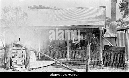 Negative - Gruppe von Männern, die auf der Veranda eines Wellblech Haus auf "Portland Downs' Bahnhof, Isisford Bezirk, Queensland, ca. 1920, eine Gruppe von Männern auf der Veranda eines Hauses auf 'Portland Downs" Station. Das Haus ist aus Wellblech gebaut. (Links auf dem Foto ist Licht - Betroffene Stockfoto