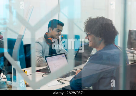 Zwei junge Männer am Computer arbeiten in Coworking Büro. Gesehen durch das Glas. Stockfoto