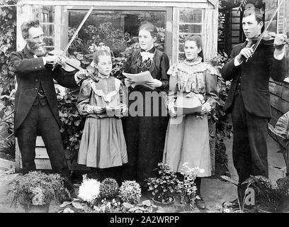 Negative - Merino Bezirk (?), Victoria, vor 1910, eine Familie, die musikalische Gruppe in einem Garten. Die zwei Männer spielen Geigen, während die Frau und zwei junge Mädchen singen. Die Sängerinnen und Sänger sind holding Kerben Stockfoto