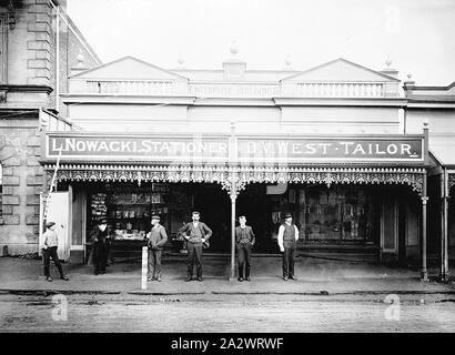 Negative - Casterton, Victoria, 1902, eine Gruppe von Männern außerhalb zwei Geschäfte bilden den Enterprize Gebäude, 1899 erbaut. Die beiden Geschäfte sind "L. Nowacki, Papierladen' und 'D. V. Westen anpassen". Die alten Mechanik Institut befindet sich auf der linken Seite. Es gibt Schmiedeeisen lacework über der Veranda des Geschäfte Stockfoto