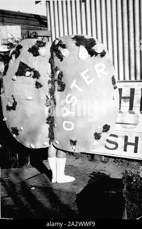 Negative - Pinjarra, Victoria, ca. 1925, ein Mädchen, ein Kostüm trägt, das eine Auster. Das Wort "Oyster" durch die "Hölle" wird angezeigt. Es si ein Zeichen hinter ihr, von denen der Buchstaben "h" sichtbar sind Stockfoto