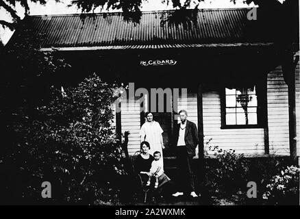 Negative - Daylesford, Victoria, ca. 1930, eine Familie, die Gruppe vor ihrem Haus "zedern" bekannt. Das Haus ist ein einfaches weatherboard mit einem Wellblechdach und Veranda. Etablierte Sträucher im Vorgarten Stockfoto