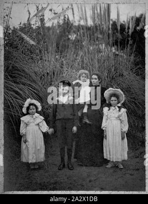 Negative - Frau und vier Kindern in einem Garten, Victoria, ca. 1900, Schwarz-weiß Kopie Negativ einer Fotografie, die Betty Anderson von Kew gehörte, und schildert Betty als Kind mit ihrer Familie. Betty (Elizabeth) war die Tochter von James Caldwell Anderson und Mary Lloyd Anderson und Grand-Tochter des renommierten Architekten Lloyd Tayler. 1889 geboren, Betty war einer von vier Geschwistern, die alle an sie überlebt. Die Familie lebte an 'Mynda", 5 Molesworth Street Stockfoto