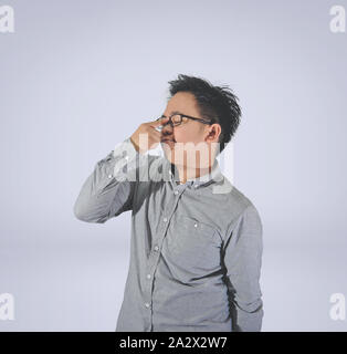 Junger Mann mit langen Ärmeln und Brillen zu machen ein lustiges Gesicht oder Mimik auf einem weißen Hintergrund. Stockfoto