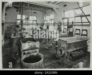 Fotografie - Hecla Elektrik Pty Ltd., Arbeitnehmer Gestaltung Komponenten aus Metall, ca. 1930, Fotografie von männlichen Fabrikarbeiter Beschichtung Metall komponenten von Hecla Heizungen, möglicherweise in die Little Bourke Street Hecla Fabrik, Melbourne. Verkleidungen für "Century" Modell Heizungen sind sichtbar neben der Wannen. Auf der linken Seite des Bildes ein Mann Komponenten wäscht vor der galvanischen Prozess. Die Verkleidungen und andere Komponenten werden dann auf Stangen geschlitzt und über die Wannen für Nickel ausgesetzt Stockfoto