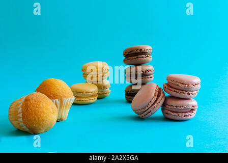 Macarons und Muffins auf blauem Hintergrund getrennt und ohne Integration Stockfoto