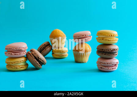 Macarons und Muffins auf einem blauen Hintergrund vollständig zwischen Ihnen integriert Stockfoto