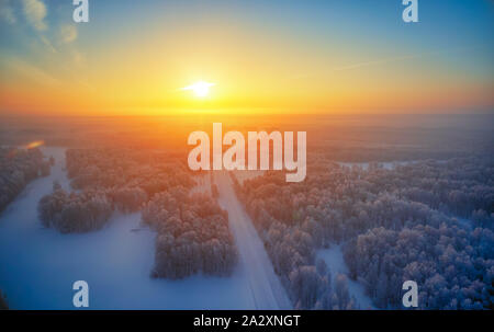 Sonne über sibirische Wald unter dem Schnee am Morgen Zeit. Sibirische ländlichen winter Sonnenaufgang Landschaft mit Birken, die mit Reif bedeckt. Luftaufnahme Stockfoto