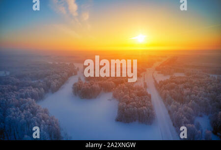 Sonne über sibirische Wald unter dem Schnee am Morgen Zeit. Sibirische ländlichen winter Sonnenaufgang Landschaft mit Birken, die mit Reif bedeckt. Luftaufnahme Stockfoto