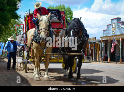 Eine rote Postkutsche erwartet die Passagiere mit zwei ruhende Pferde und Cowboys in historischen Tombstone, AZ, USA Stockfoto