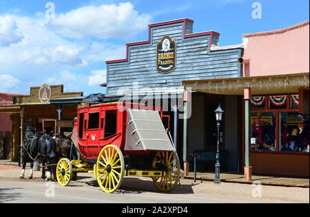 Eine rote Postkutsche mit gelben Räder erwartet die Passagiere mit zwei erholungstagen Pferde neben Storefronts in historischen Tombstone, AZ, USA Stockfoto