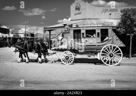 Eine antike Stagecoach von zwei Pferden geführt von Cowboy Treiber mit Touristen in Tombstone, AZ, USA an Bord gezogen, in Schwarz und Weiß Stockfoto