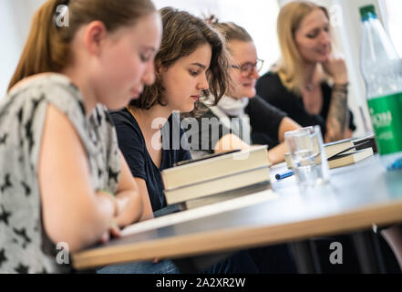 20. August 2019, Hessen, Frankfurt/Main: Die Mitglieder der "JungeMedienJury" (Jmj) Mia (14), l-r), Jette (15), Linnea (15) sowie der Bibliothekar Belinda Smanka am Tisch sitzen an einer der Sitzungen in der Frankfurter Zentrale Bibliothek. Im Ausschuss, 13- bis 16-Jährige aktuelle Buchtitel diskutieren und am Ende ein Sieger gewählt und weitere Empfehlungen gemacht werden. Foto: Frank Rumpenhorst/dpa Stockfoto