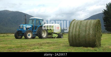 Greymouth, Neuseeland, 22. Februar 2008: Schlepper Pressen bis großen Rundballen des Grases für Silage, West Coast, South Island, Neuseeland Stockfoto