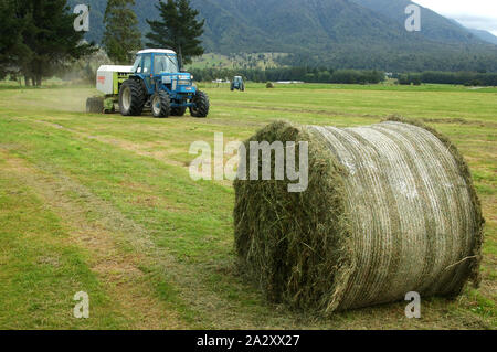 Greymouth, Neuseeland, 22. Februar 2008: Schlepper Pressen bis großen Rundballen des Grases für Silage, West Coast, South Island, Neuseeland Stockfoto