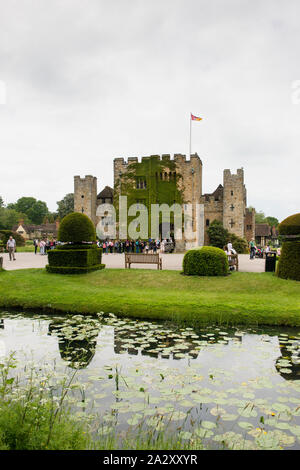 Außerdem befinden sich das Hever Castle, Kindheit Anne Boleyn's Home, Hochformat, reflektierendes Wasser im Vordergrund, Flagge über Schloss, blauer Himmel und Touristen in zurück fliegen. Stockfoto